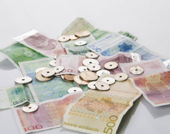 norske sedler og mynter i en haug strødd på et bord